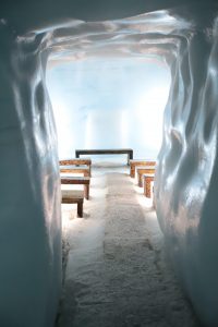Several small tables are the end of an icy tunnel that puts you in mind of a church built of ice