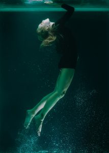 woman in black shirt and green shorts underwater