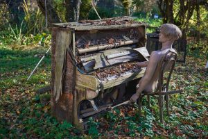A dilapidated piano rotting in the woods as half a mannequin plays it